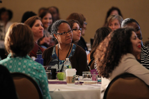 woman seated at event table listening intently