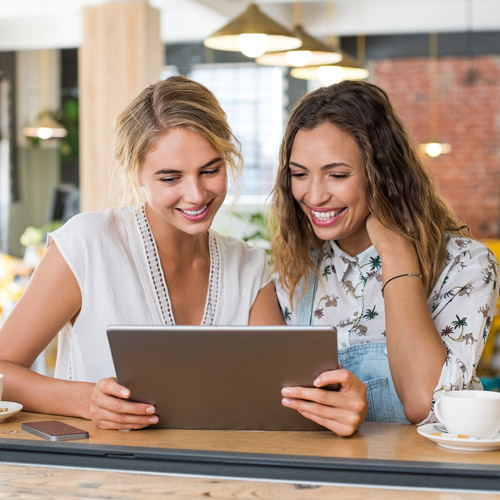 two women smiling looking at tablet